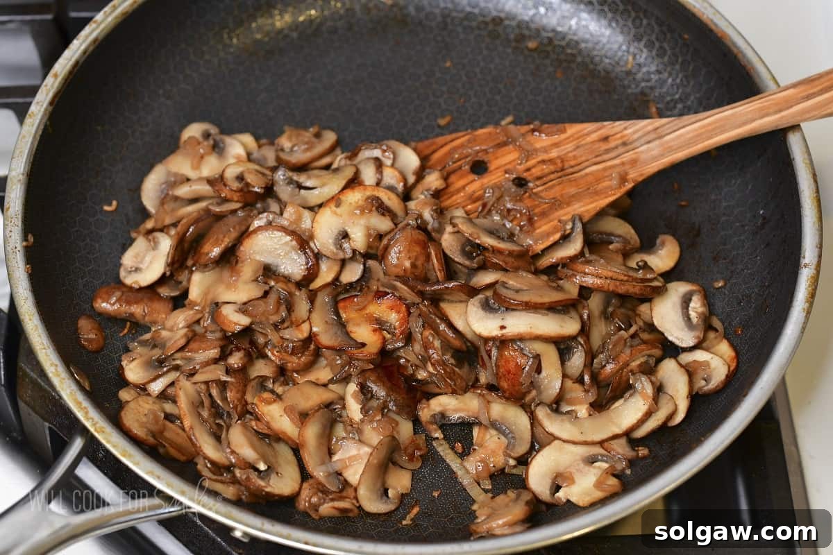 sautéed sliced mushrooms in a cooking pan, golden brown and perfectly tender.