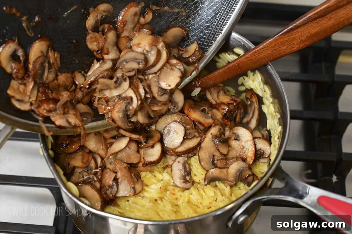 adding sautéed mushrooms to the pot with orzo, showing the final assembly.