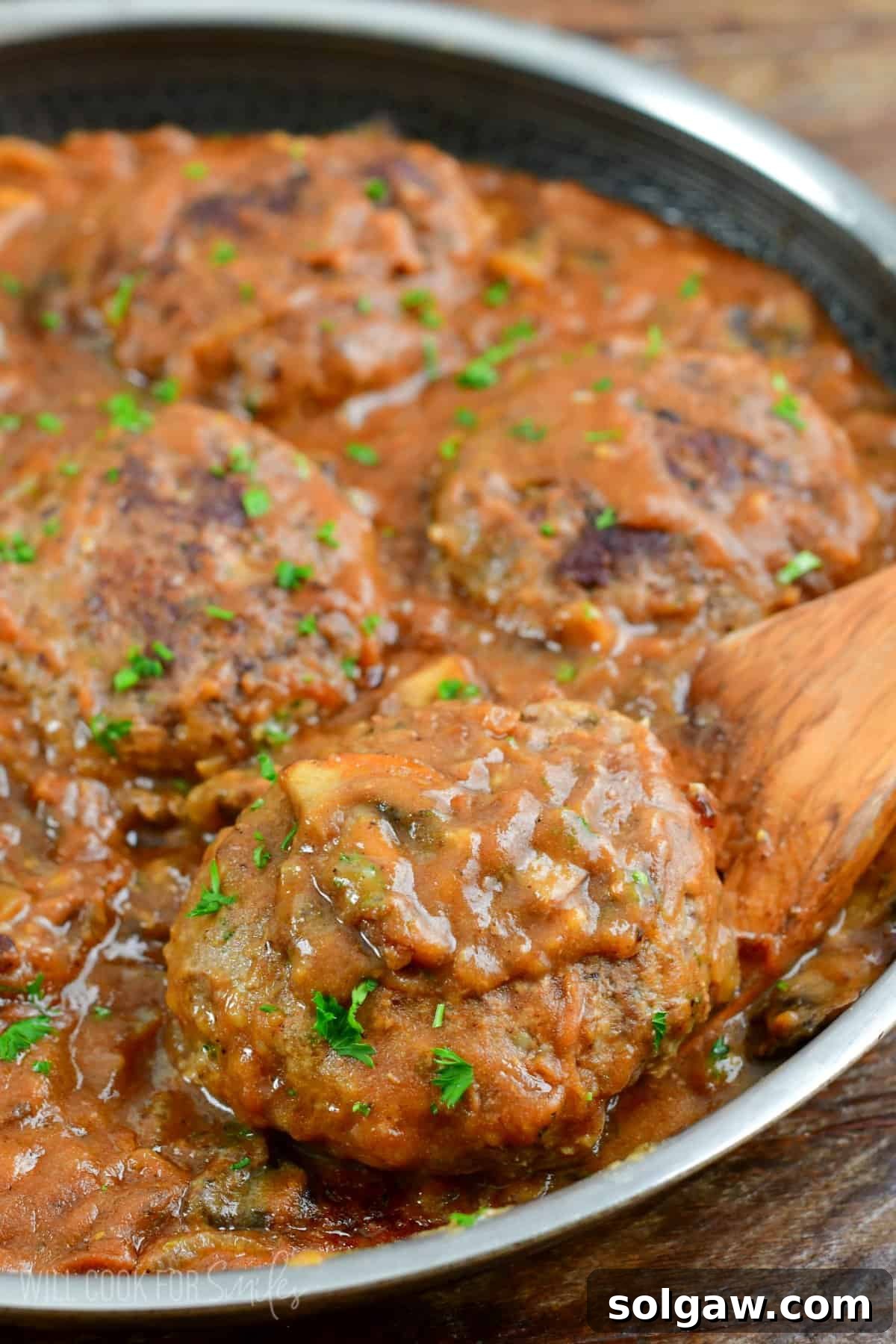 taking one of the Salisbury streaks out of the pan with a wooden spatula.