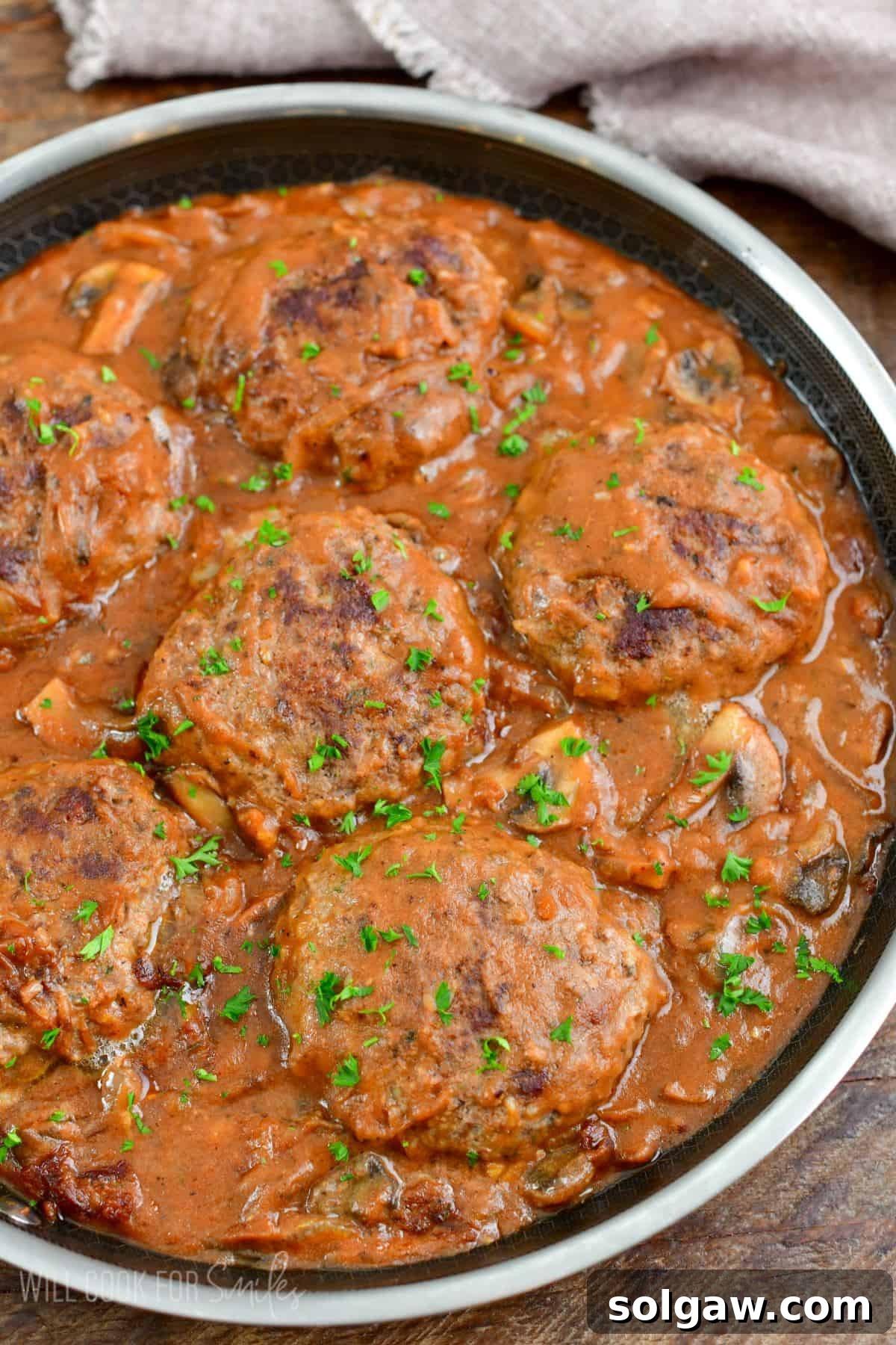 Salisbury Steak in a pan with parsley on top as garnish.