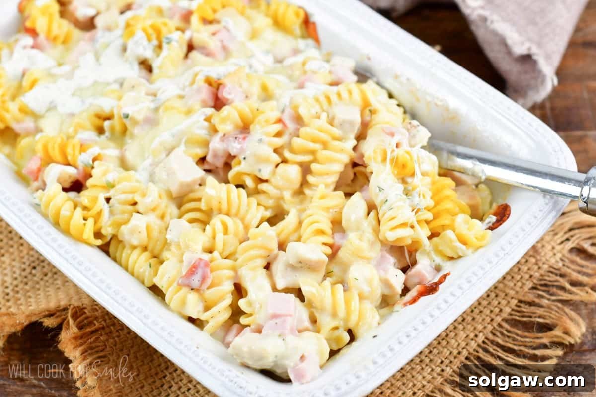 Chicken Cordon bleu chicken casserole in a baking pan with a metal spoon.