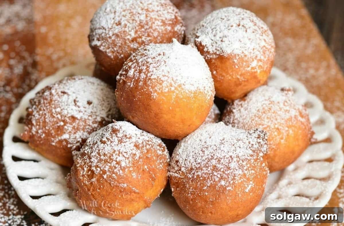 several stacked donut holes on a plate with powdered sugar.