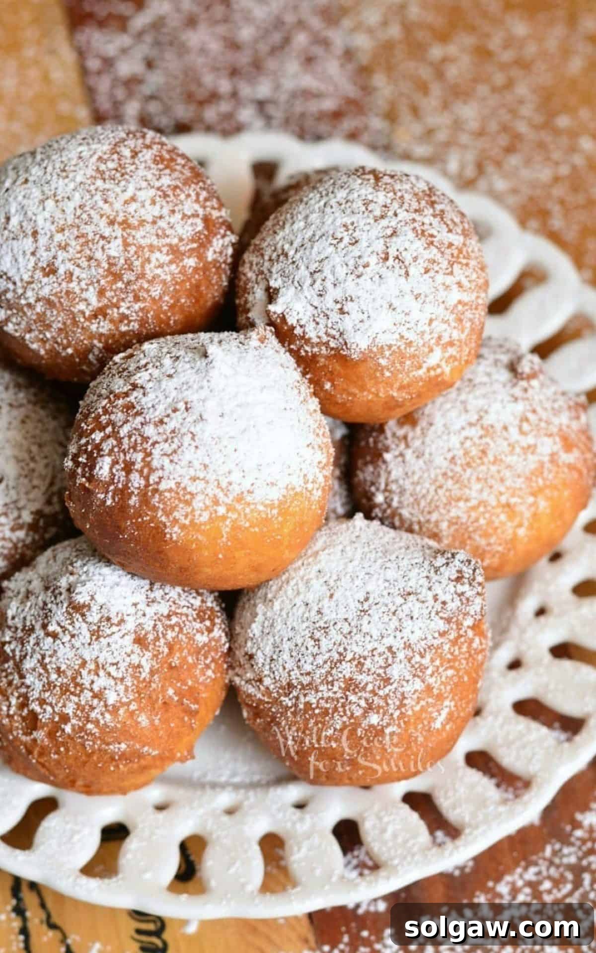 stacked ricotta donuts on a plate with powdered sugar.