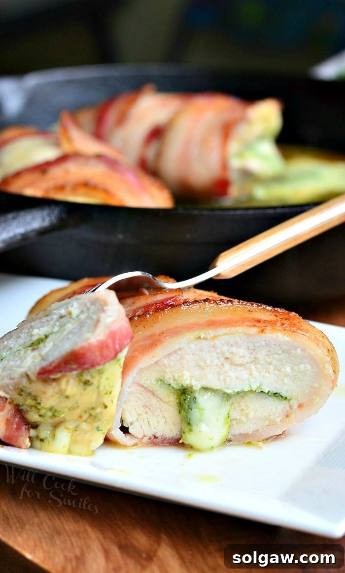 A close-up of Bacon Wrapped Pesto Mozzarella Stuffed Chicken Breast, showcasing the melted cheese and crispy bacon texture.