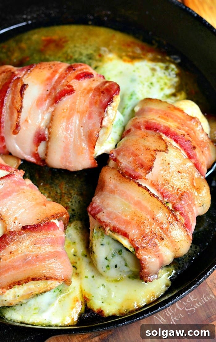 Top-down view of a cast iron skillet filled with golden-brown bacon wrapped pesto mozzarella chicken breasts, fresh out of the oven.