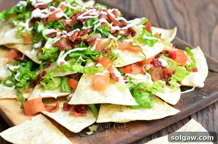 BLT Nachos with lettuce, tomato, and bacon on a wood cutting board