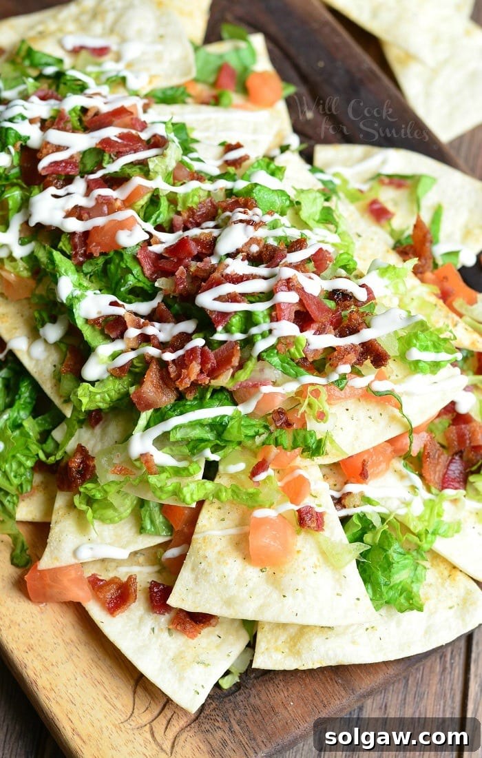 View from above of a wooden platter with BLT nachos and homemade baked cool ranch tortilla chips on a wooden table