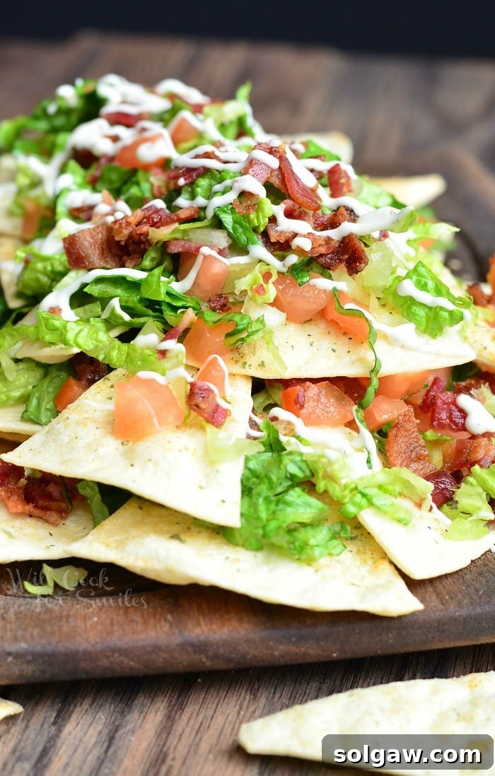 BLT Nachos with lettuce, tomato, and bacon, on a wood cutting board