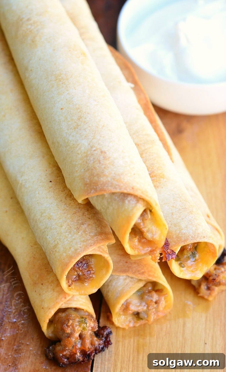 top view photo of Jalapeño Sausage and Cheese Taquitos stacked on a cutting board