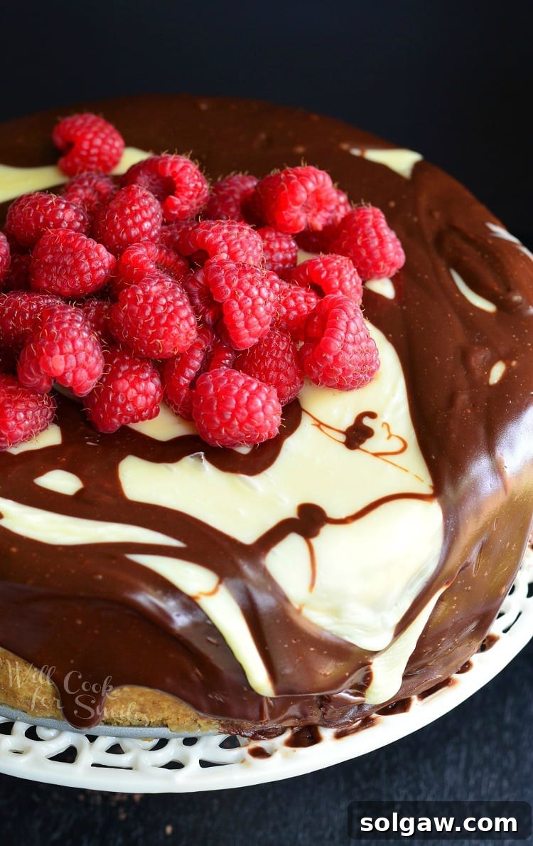 Top view of chocolate Ganache and Raspberry Cheesecake with raspberries on top on a cake stand