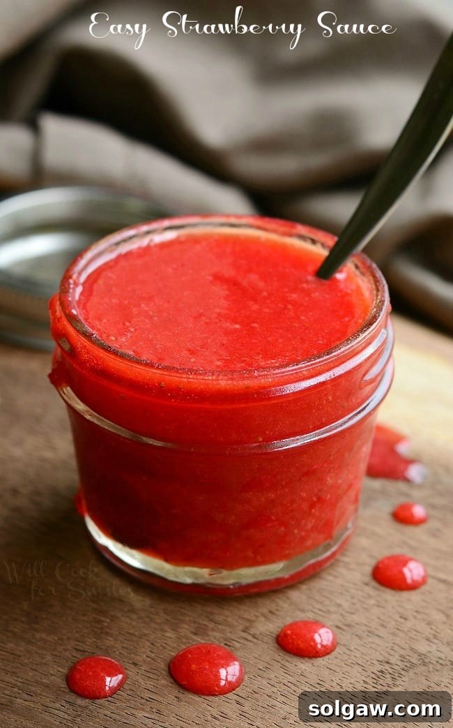 Homemade Easy Strawberry Sauce in a clear glass jar with a spoon, ready to be used as a topping or ingredient.