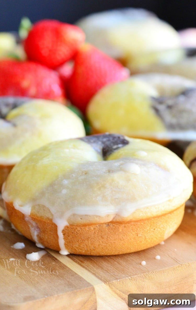Close-up view of a Neapolitan Glazed Doughnut showing the three distinct layers of chocolate, vanilla, and strawberry and the glossy glaze.
