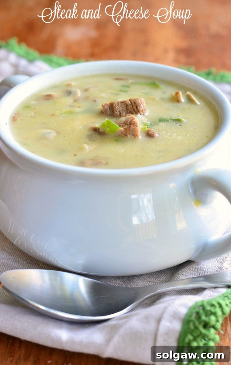 Steak and Cheese Soup in a white soup bowl with a spoon over the front