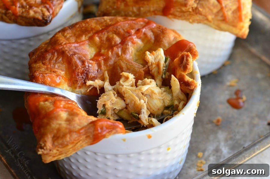 A close-up of a Buffalo Chicken Pot Pie in a ramekin with a fork lifting out a spoonful of creamy filling