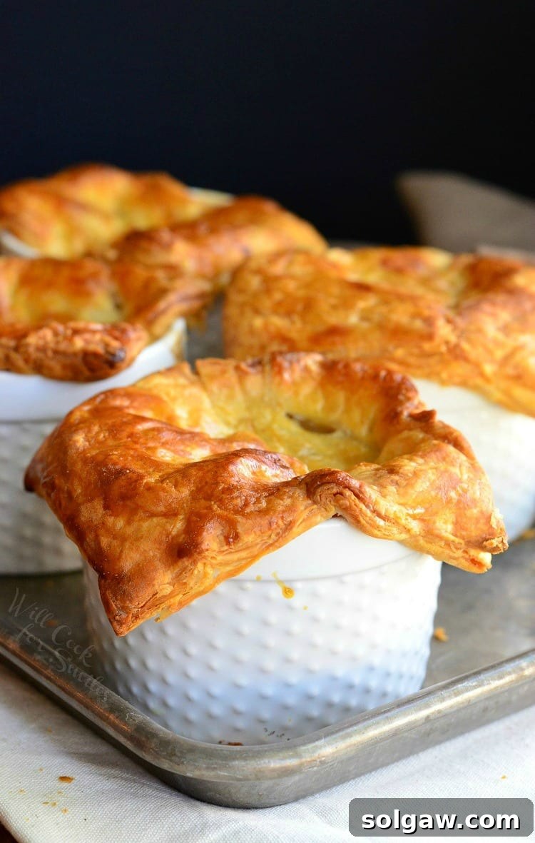 Four golden-brown Buffalo Chicken Pot Pies with flaky pastry crusts on a baking sheet, ready to eat