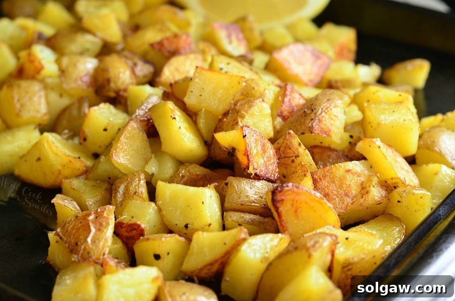 Horizontal shot of golden Truffle Lemon Pepper Roasted Potatoes scattered on a baking sheet, ready to serve.