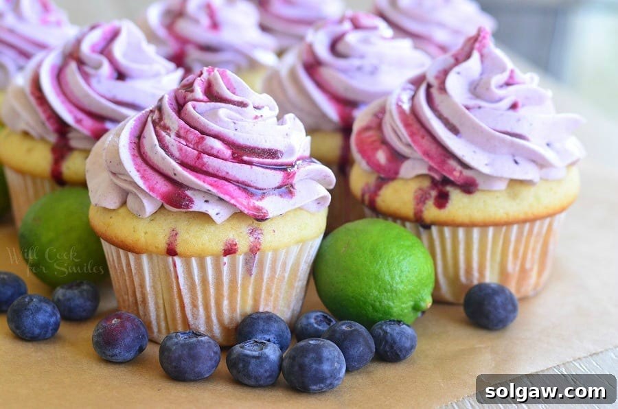 Tangy Blueberry Key Lime Delights 4 Cupcakes with Fresh Blueberry Cream Cheese Frosting on a cutting board with blueberries and limes