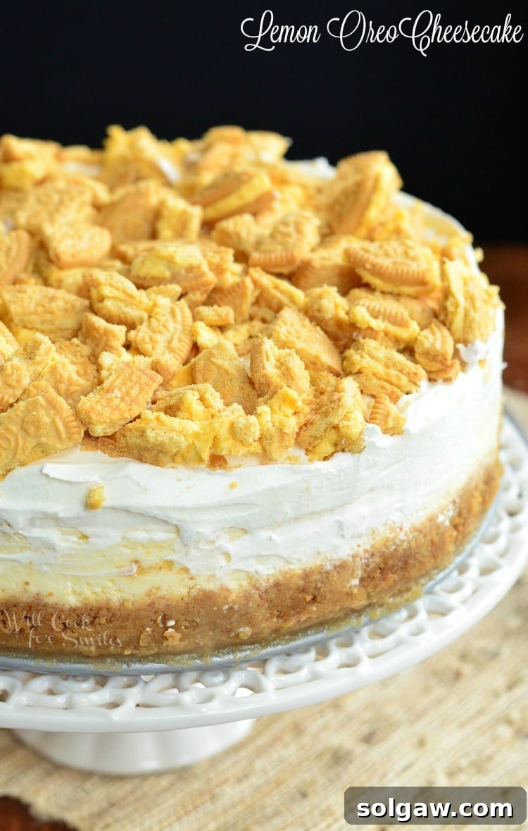 Lemon Oreo Cheesecake with crushed cookies on top on a cake stand