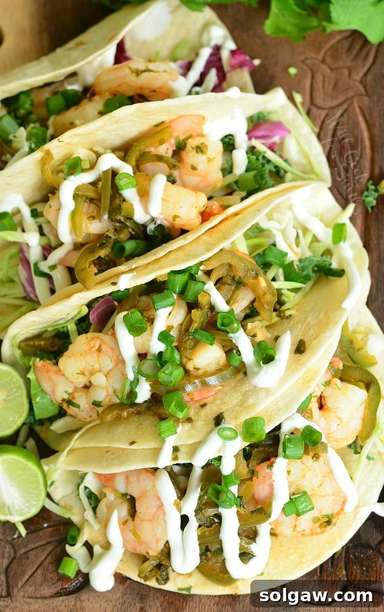 Top view of tequila Lime Shrimp Tacos with sour cream and green onions on top