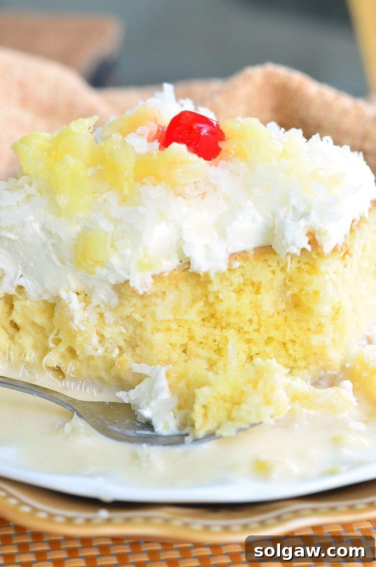 Decorative plate with a slice of pina colada tres leches cake with a fork on the plate next to the slice