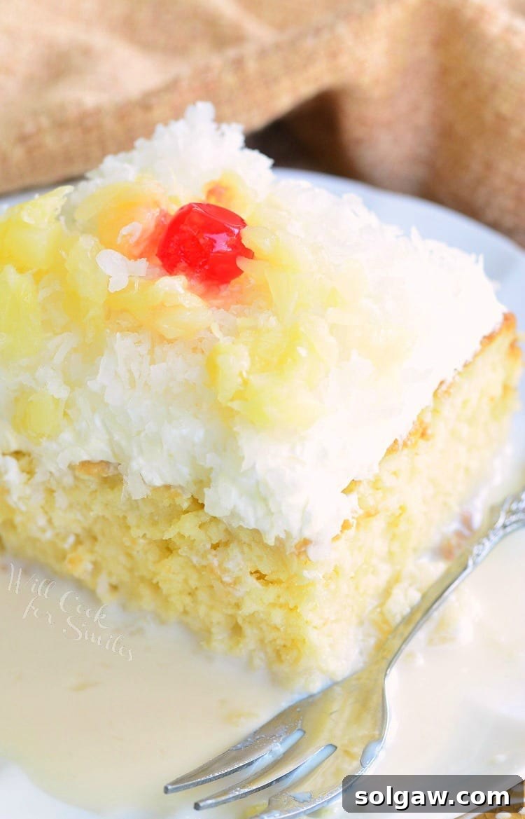 A single slice of Pina Colada Tres Leches Cake, showcasing the rich texture and vibrant tropical garnishes, ready to be enjoyed.