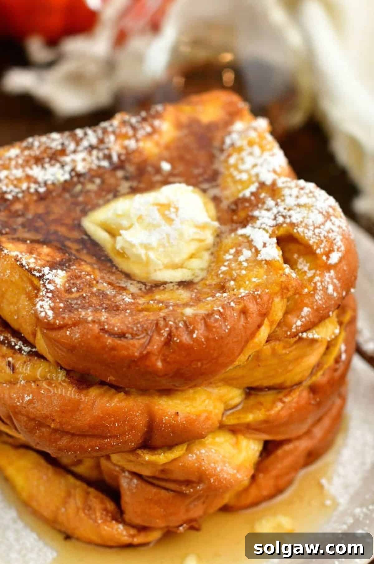 Spiced Pumpkin French Toast 2 several slices of pumpkin French toast stacked on the plate topped with butter and powdered sugar.