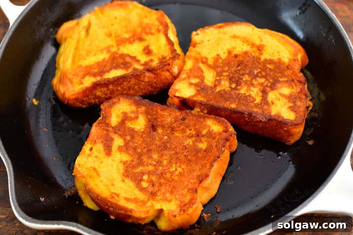 Spiced Pumpkin French Toast 5 three cooked sliced of French toast on a cooking pan.