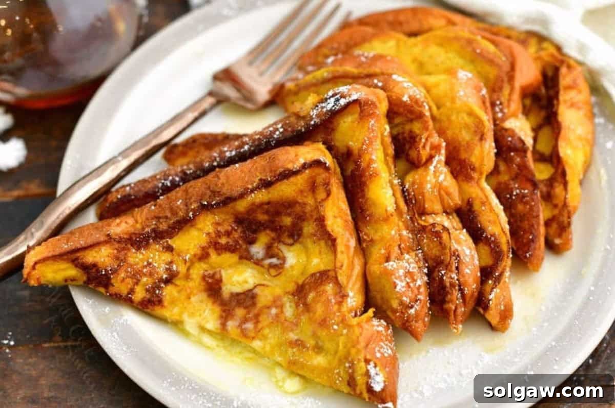 Spiced Pumpkin French Toast 6 Pumpkin French toast slices on the plate cut in half and stacked on the plate with butter and powdered sugar.