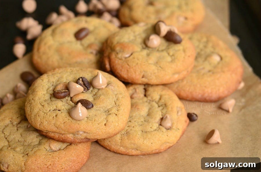 Cappuccino Cookies stacked up on parchment paper with chocolate chips and cappuccino chips around it and on top