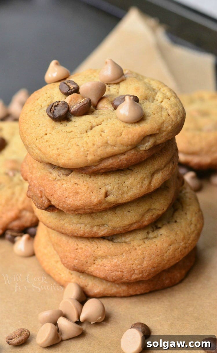 Cappuccino Cookies stacked up on parchment paper with chocolate chips and cappuccino chips around it and on top