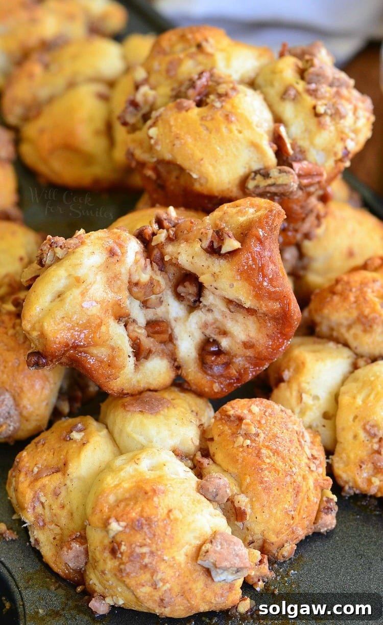 butter pecan pull apart biscuits stacked up on a baking sheet, golden brown with melted butter and chopped pecans