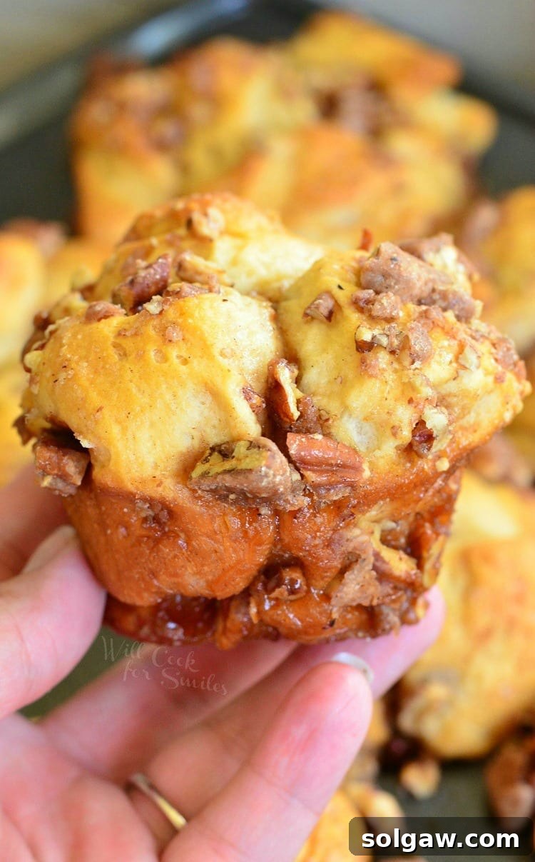 holding a pull apart muffin in my hand with candied pecans and glaze dripping off, ready to eat