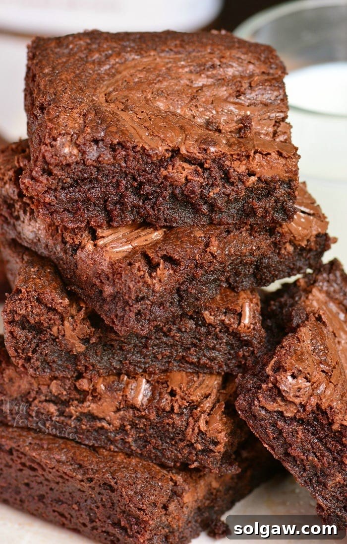 nutella brownies stacked up on a white plate, showcasing their fudgy texture.