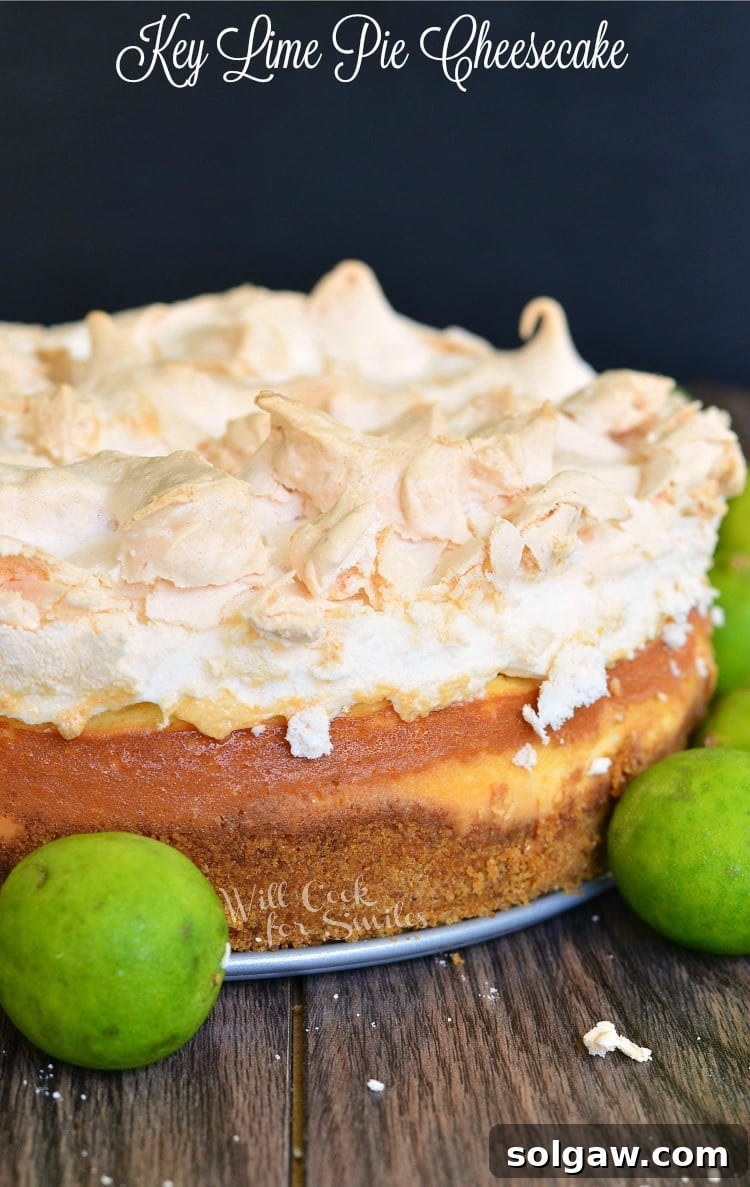 Zesty Key Lime Pie Cheesecake 2 A stunning Key Lime Pie Cheesecake with a towering meringue top, resting on a rustic wooden table, surrounded by fresh green key limes, ready to be served.