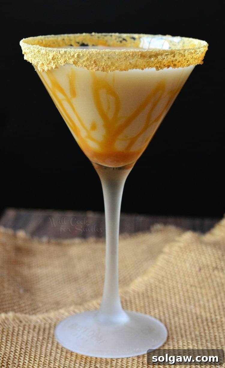 A stunning Caramel Cake Martini served in an elegant martini glass, adorned with a luxurious caramel topping around the rim and delicate drizzles inside, resting on a textured burlap tablecloth. The lighting highlights the rich, golden hues of the drink.