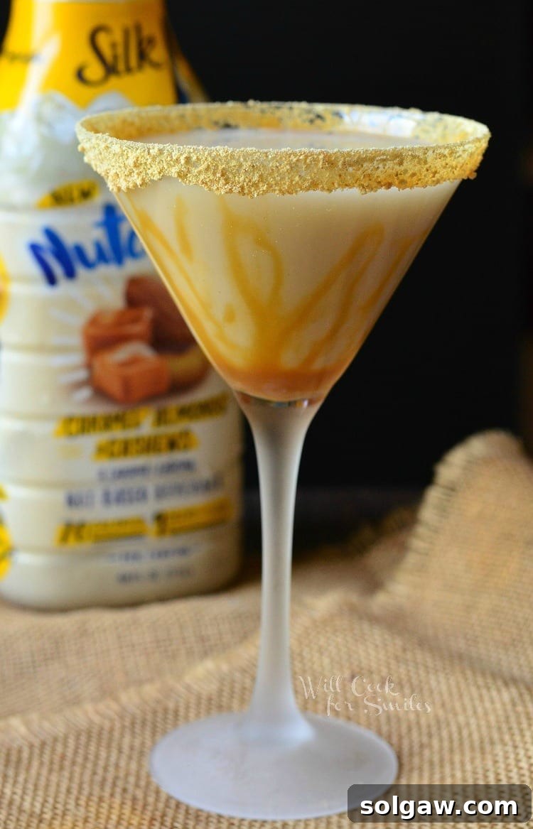 Another beautiful shot of the Caramel Cake Martini in a martini glass, with thick caramel elegantly drizzled around the rim and down the sides of the glass, placed on a rustic burlap surface.