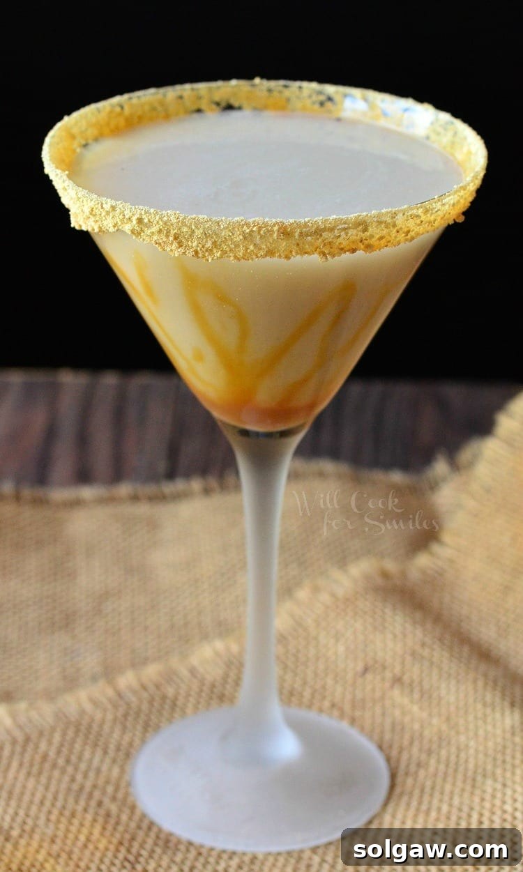 The Caramel Cake Martini, beautifully presented in a martini glass with intricate caramel drizzles, creating an inviting and luxurious visual, perched on a textured burlap cloth.