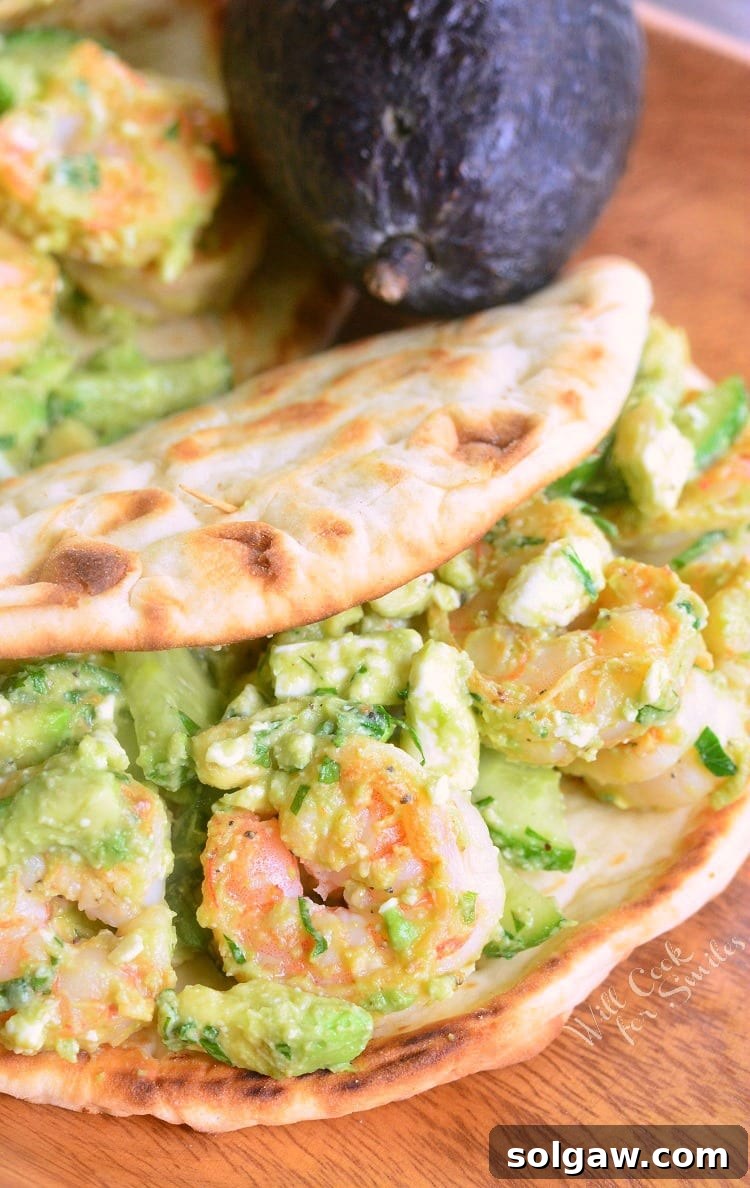 Avocado Shrimp Flatbread Sandwich on a cutting board with a fresh avocado in the background, highlighting key ingredients