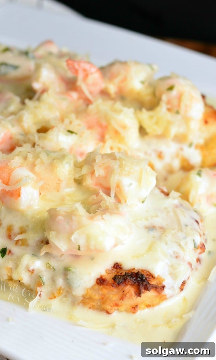 Oven Fried Chicken topped with shrimp and a Creamy Fontina cheese Shrimp Sauce on a white plate