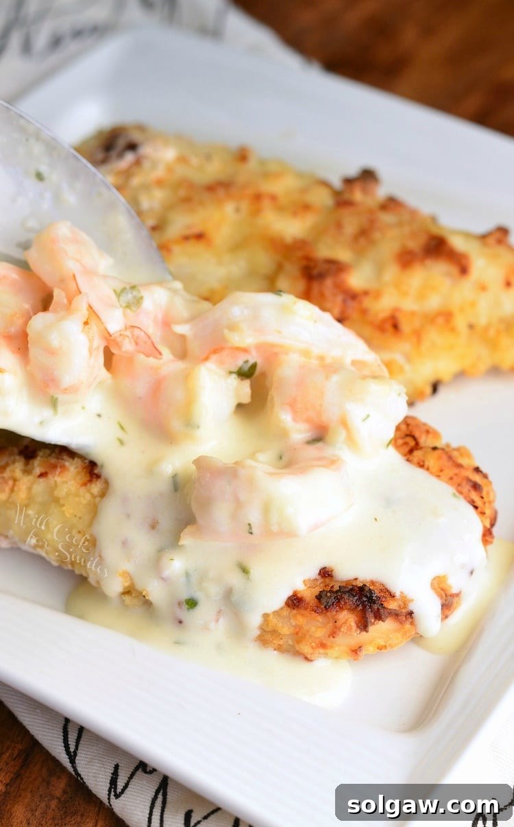 Oven Fried Chicken topped with shrimp and a Creamy Fontina cheese Shrimp Sauce on a white plate