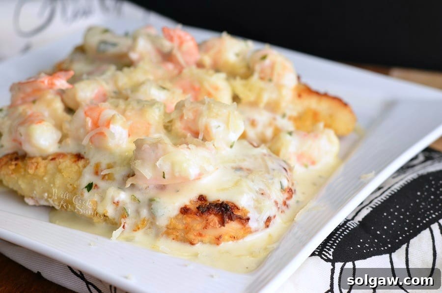 Oven Fried Chicken topped with shrimp and a Creamy Fontina cheese Shrimp Sauce on a white plate