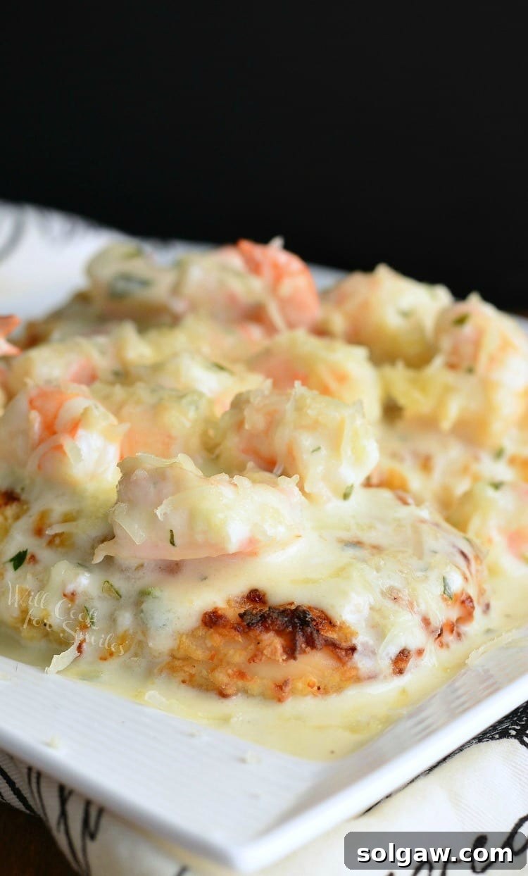 white decorative plate with oven fried chicken topped with creamy fontina shrimp sauce as viewed from above