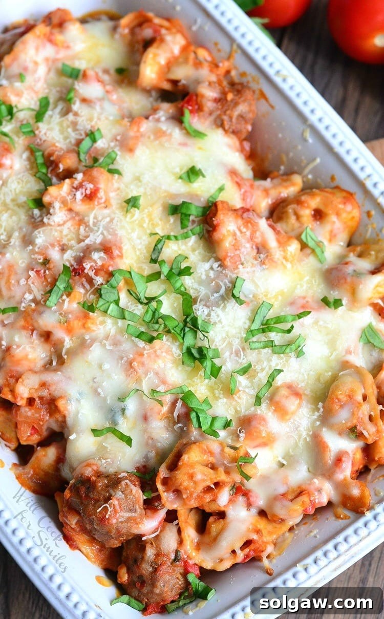 Hearty Chicken and Sausage Tortellini Bake 3 Chicken, Sausage, and pasta with cheese on top in a white casserole dish