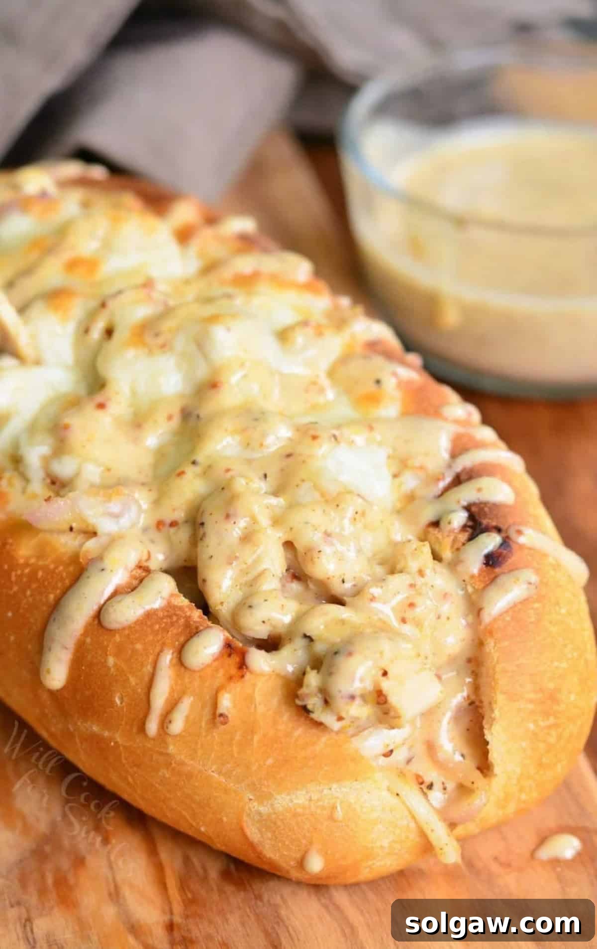 baked sub packed with chicken, melted cheese on top, and more white BBQ on top.