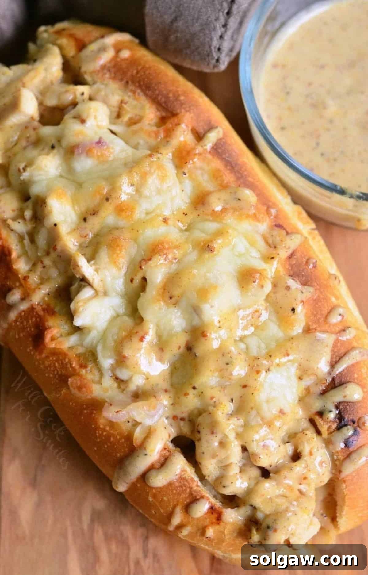 baked chicken sub sandwich packed with diced chicken, melted cheese, and white BBQ sauce on top.