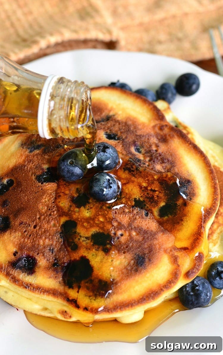 Single serving buttermilk pancakes topped with syrup and blueberries as viewed from above