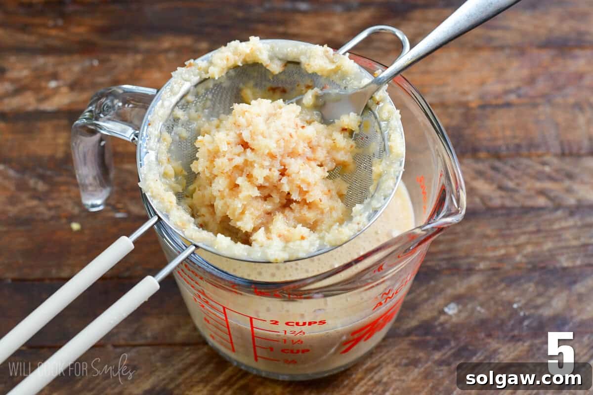 Tropical Coconut Syrup 6 Straining the coconut in a small mesh strainer into a measuring cup.