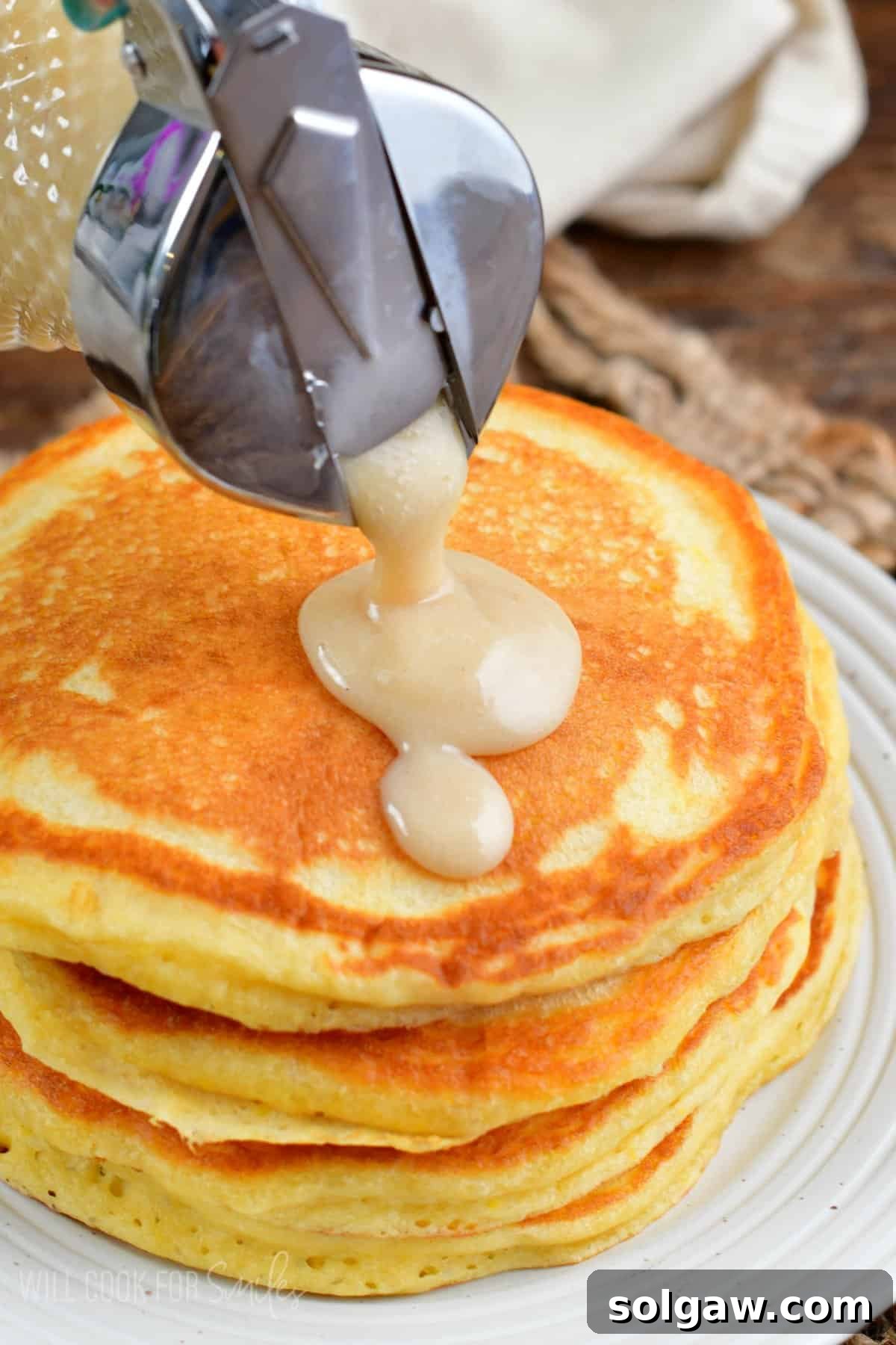 Tropical Coconut Syrup 8 pouring coconut syrup over pancakes on a plate.
