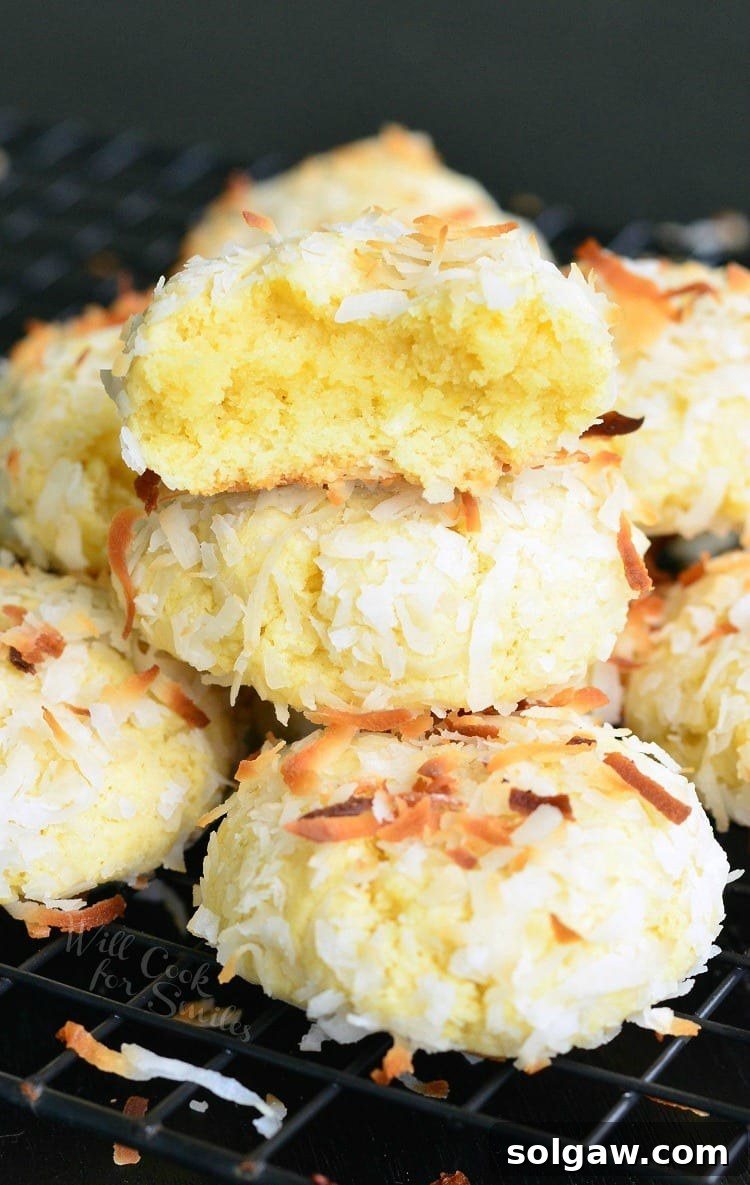 Stack of golden-brown Coconut Pudding Cookies with toasted coconut flakes on a cooling rack, showcasing their inviting texture.