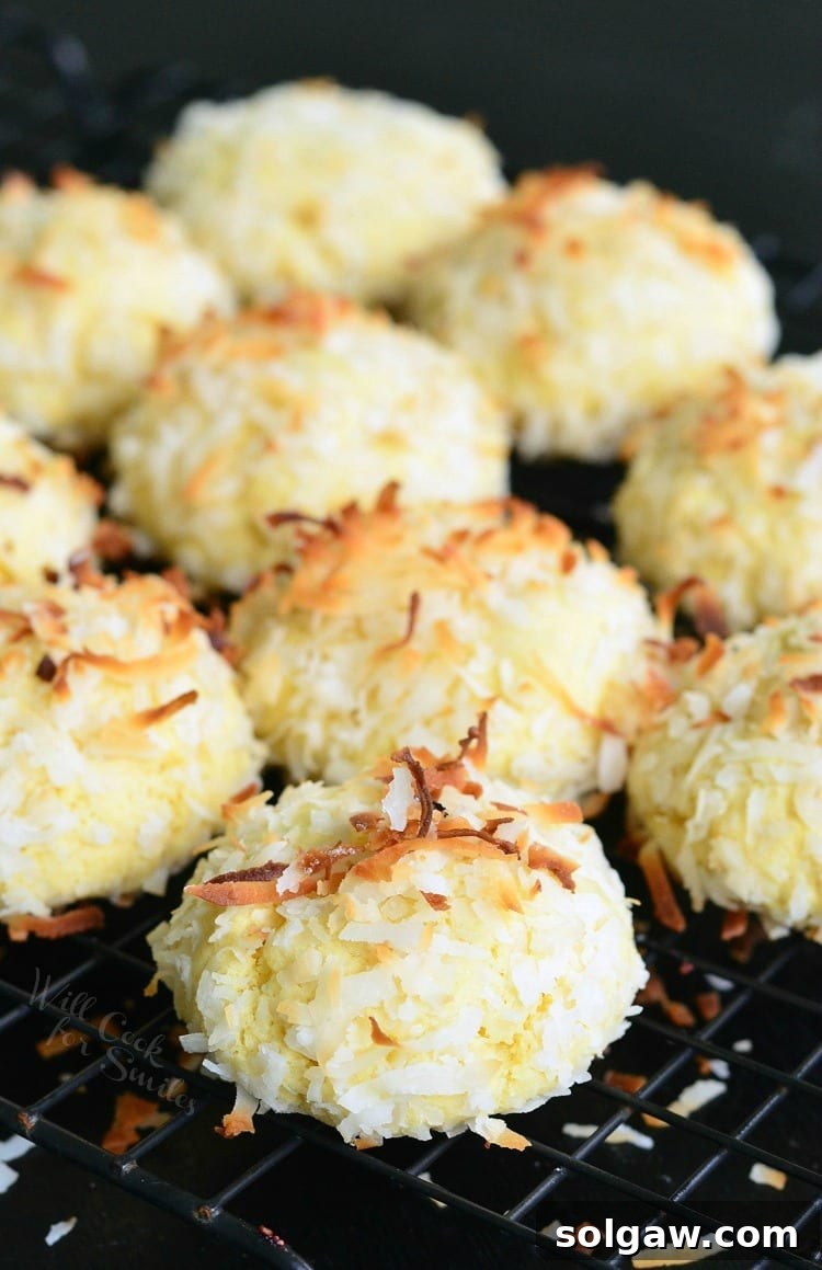 A stack of three Coconut Pudding Cookies on a wire rack, showcasing their fluffy texture and golden toasted coconut flakes, ready for a delicious treat.